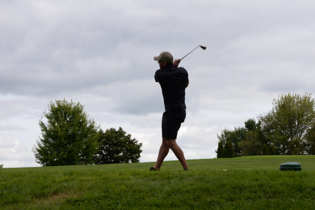 photo of a person outside swinging a golf club on a golf course